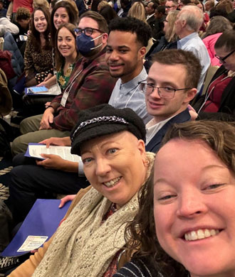 A group of Neurodiversity at Work staff and community members in a selfie from Developmental Disabilities Day. They are sitting in a row of seats among a large crowd.