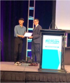 A man presents Dr. Hyeog-Geol Shin with an award.