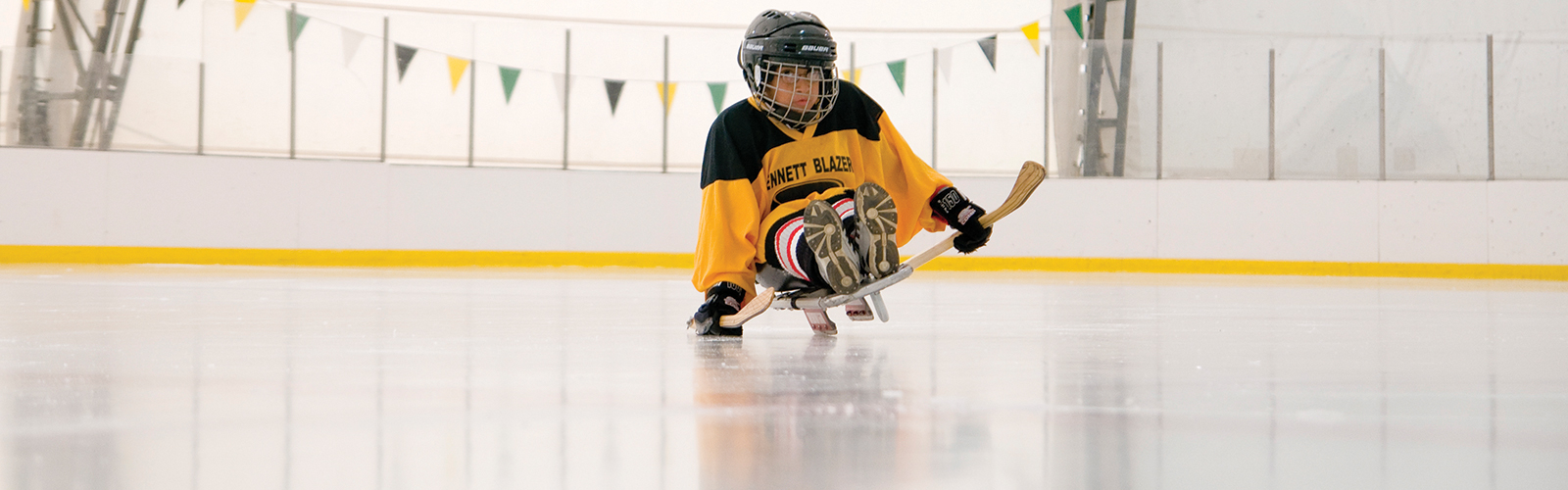 A paralyzed child playing hockey in an adaptive sports program with a focused look on her face.