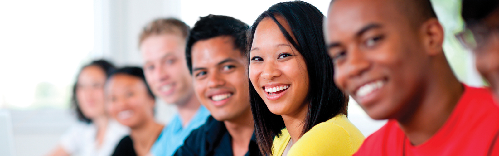 A diverse group of adults together in a line smiling.