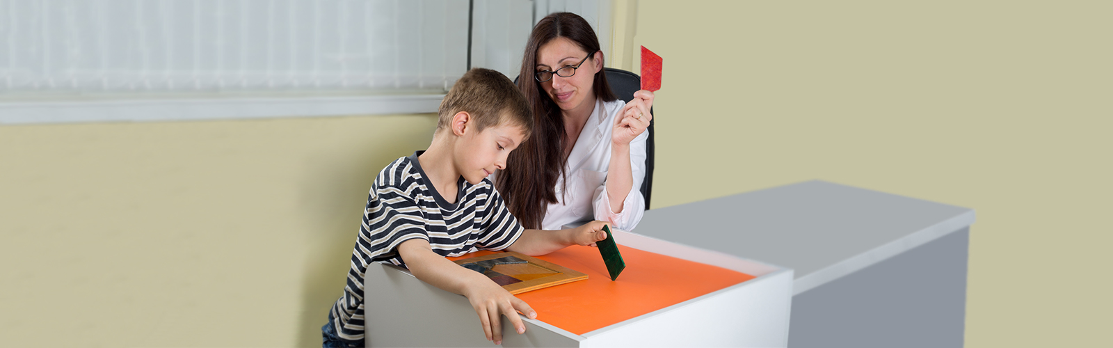 A child puts together a puzzle of shapes with help from an adult.