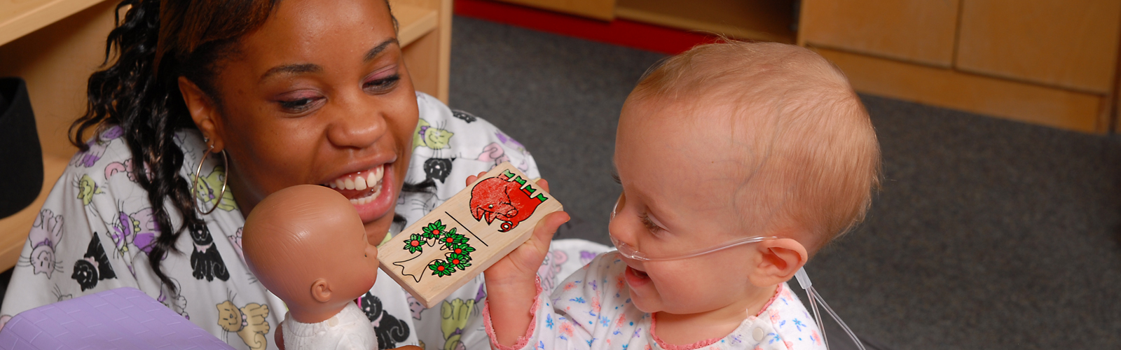 Patient Elizabeth plays with a baby doll alongside a therapist