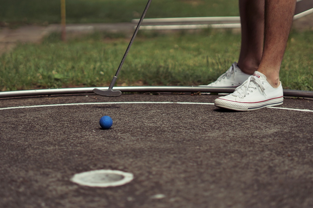 A golf ball mid-motion heading towards a hole