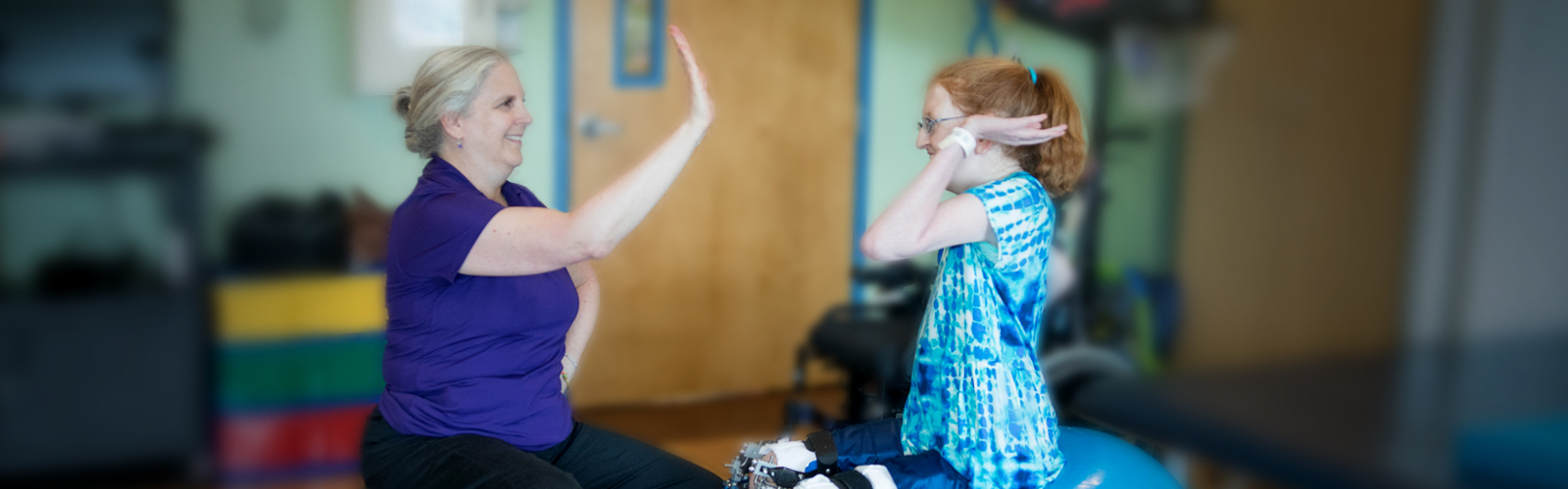 Kennedy Krieger patient Ellie high-fives a therapist