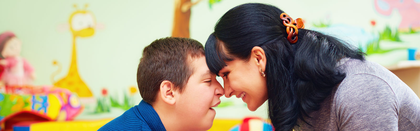 Young boy and woman sitting face to face, with foreheads touching.