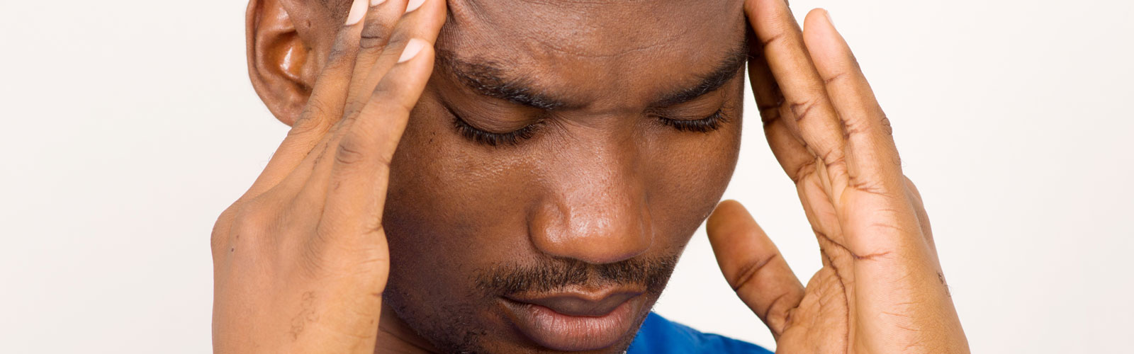 Distressed man holds his fingertips at the side of his temple. 