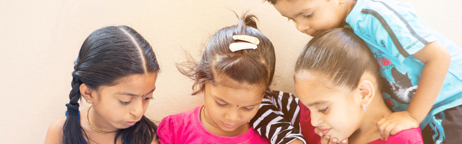 Four young children looking at tablet. 