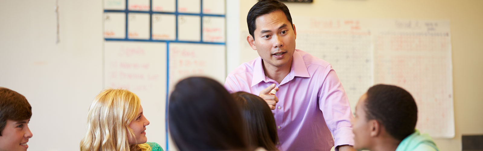 Man leads group discussion. He is standing and facing the camera, with the rest of the group sitting down.