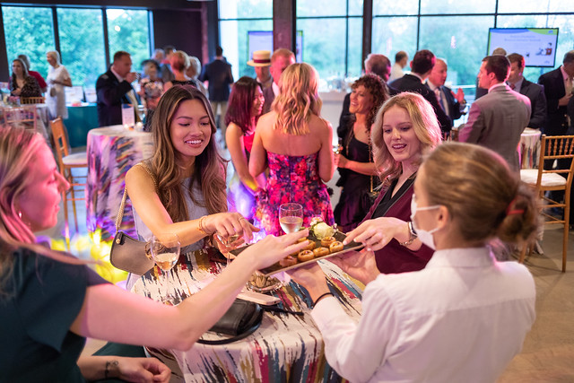 A table of attendees at Hats & Horses receive food from a server.