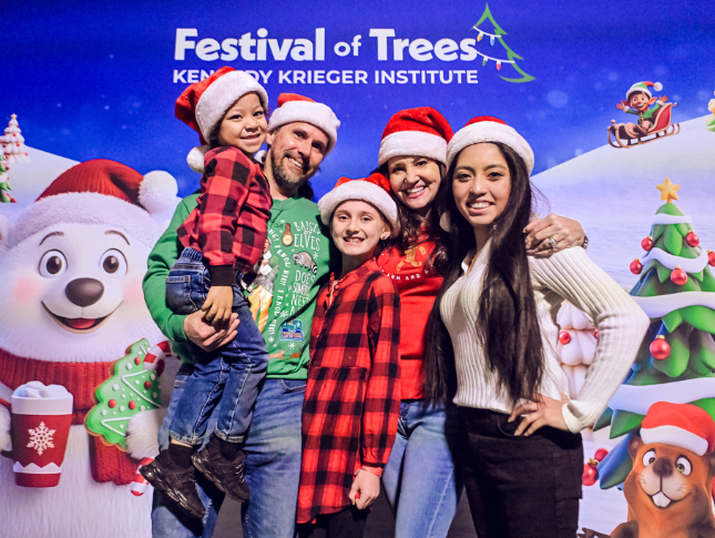Family poses in front of a festive backdrop.