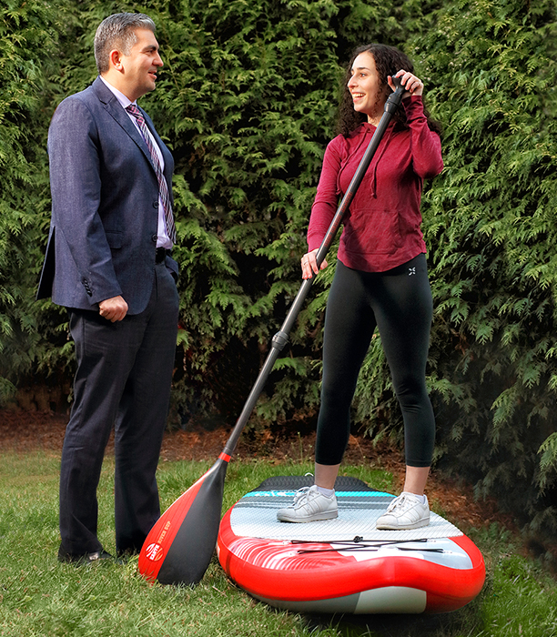 Andrea standing on a paddle board in the grass.