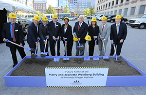 Guests line up in a row and hold shovels during the groundbreaking ceremony.