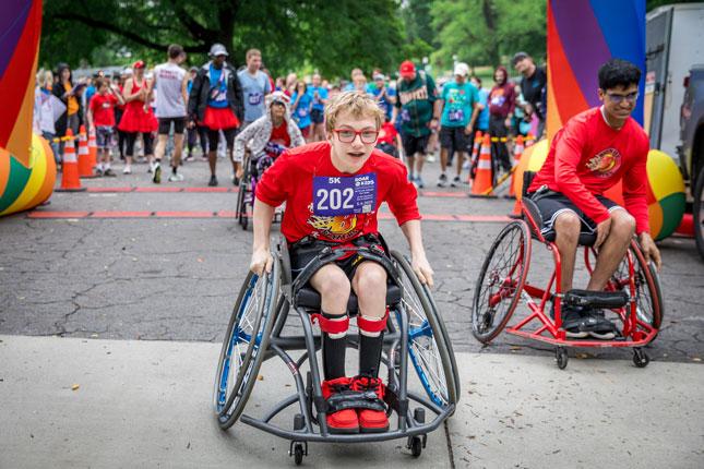 Two adaptive athletes cross the finish line at ROAR for Kids.