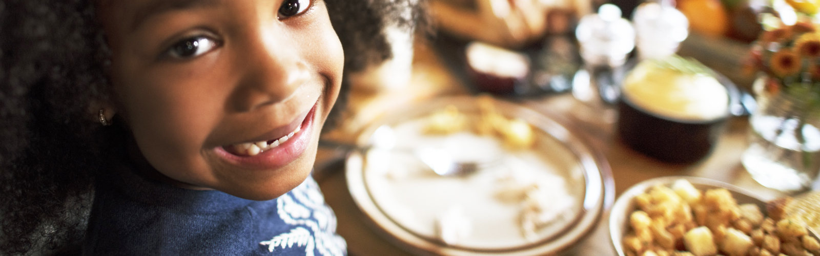 A young girl sits at a table with food.