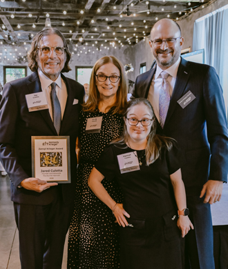 Jay Culotta is joined by his wife Cindy and daughter Hannah as he receives an award from Kennedy Krieger president and CEO Dr. Brad Schlaggar.