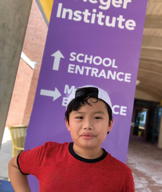 A student stands in front of a Kennedy Krieger School's entrance sign.