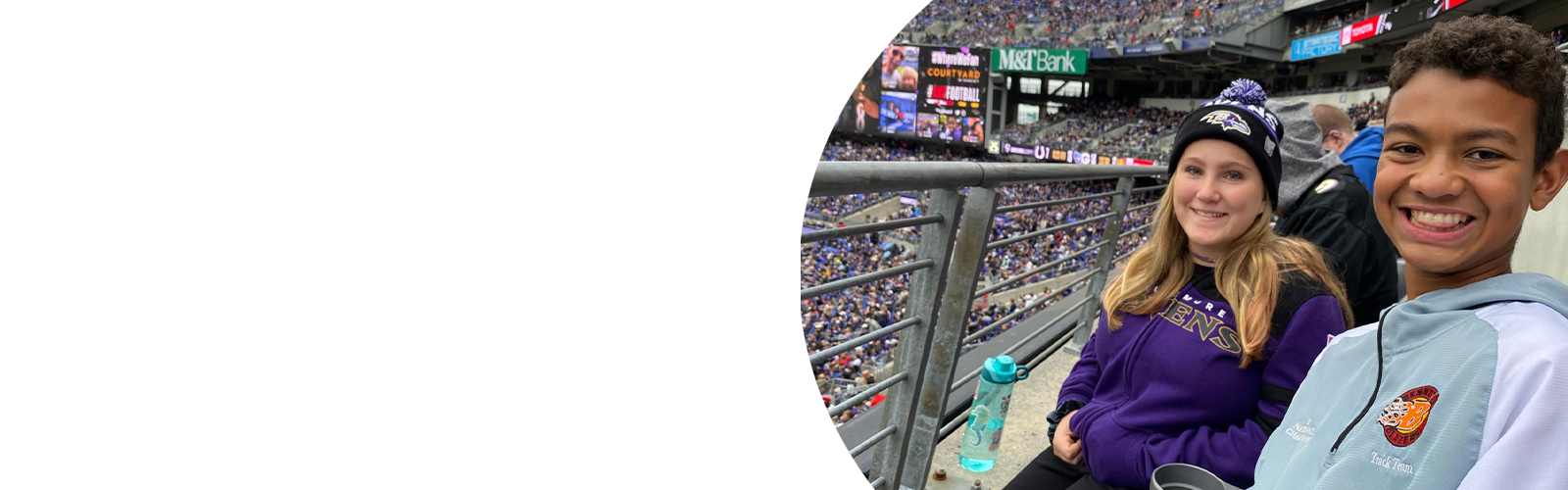 Two teenagers smile while sitting in the stands at a Baltimore Ravens game.