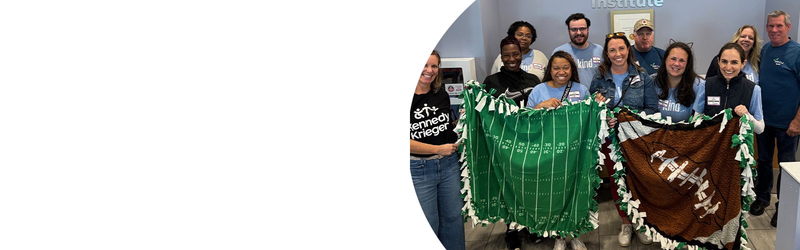 A group of SECU employees and Kennedy Krieger staff members hold blankets that were made at a volunteer event.