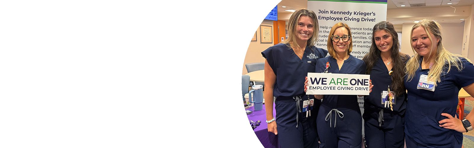Four Kennedy Krieger Nurses smile as one of them holds a We Are One Employee Giving Drive sign.