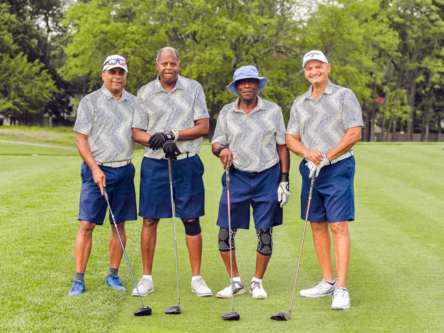 Four men stand on the green at the Center for Autism Golf Outing.