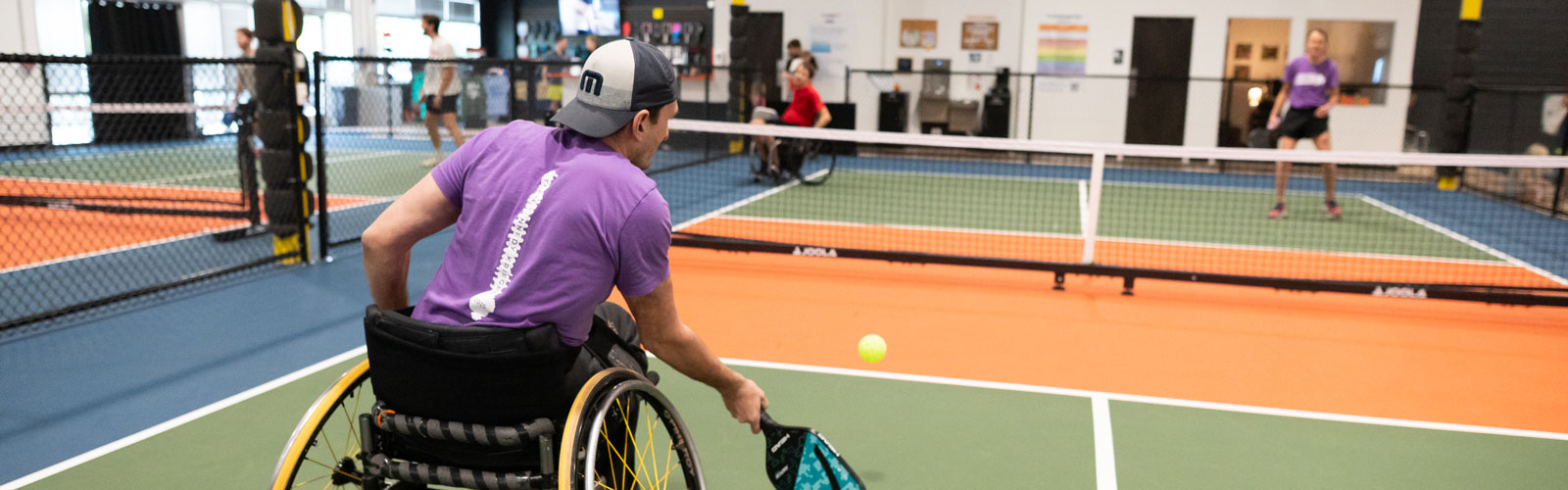 An adaptive and non-adaptive athlete playing pickleball.