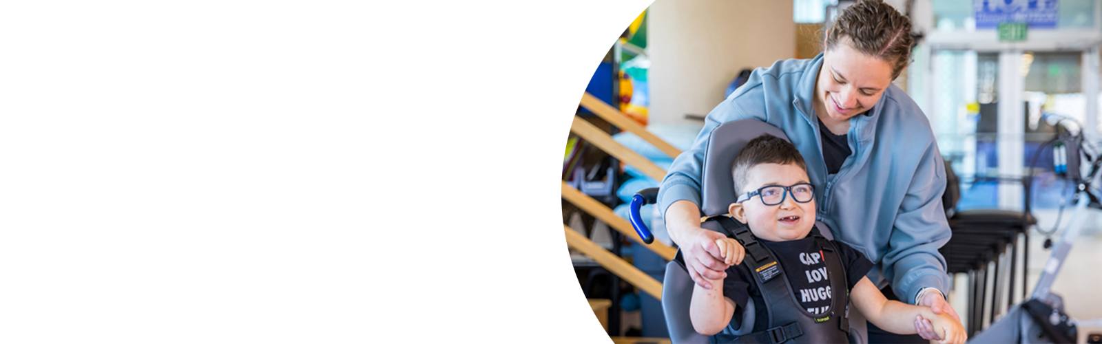 A young boy and his physical therapist smile during an appointment at Kennedy Krieger