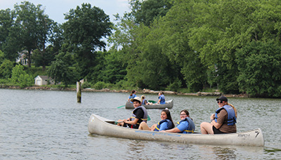 Four campers riding in a canoe on a body of water.