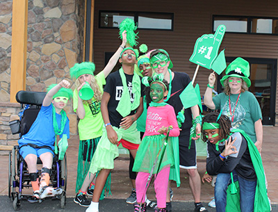 Kids huddled together all posing and wearing bright green colors.