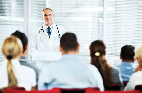 A doctor gives a presentation inside a conference room.