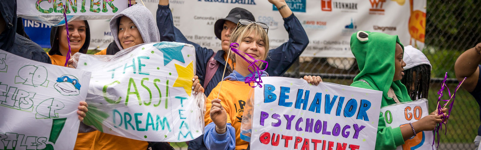 A group of ROAR attendees stand in front of the 2025 sponsorship banner