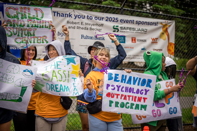 A group of ROAR attendees stand in front of the 2025 sponsorship banner.