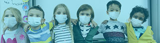 A group of kids together posing and wearing masks.