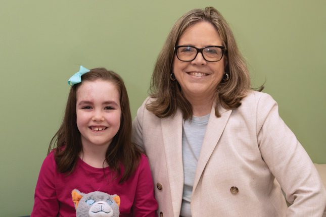 Dr. Anne Comi and a young girl with Sturge-Weber syndrome sit next to each other and smile.