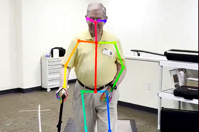 A man using a cane walks on a treadmill while participating in a motion-capture movement study