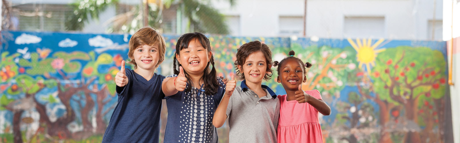 Four children of different races standing shoulder to shoulder with their thumbs up.