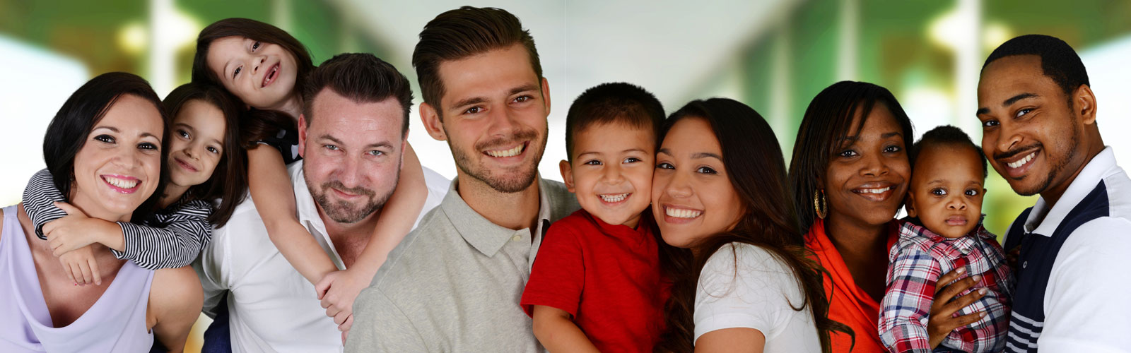 Families of multiple races stand in front of a green and white backdrop.