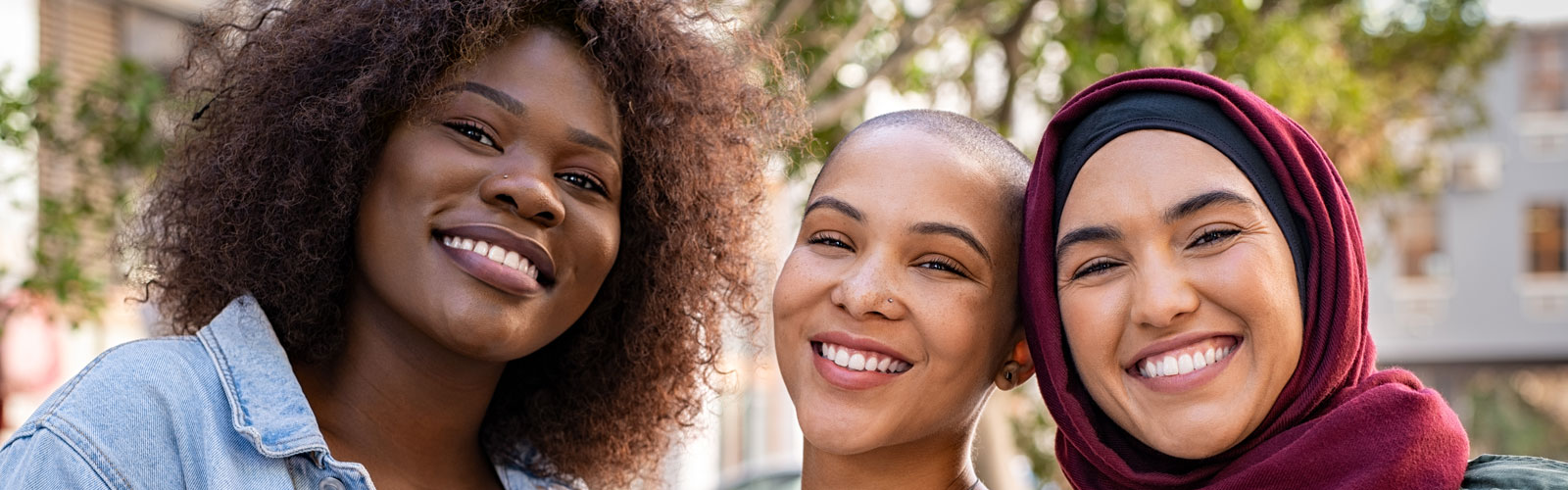 Three women of different races pose for a photo.