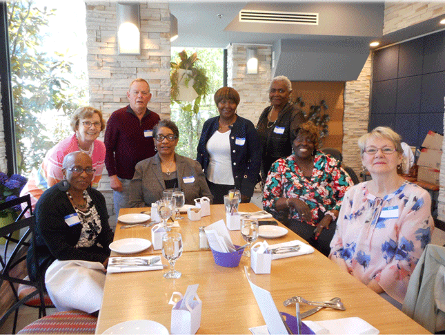 A group of alumni gather around a table at an event.