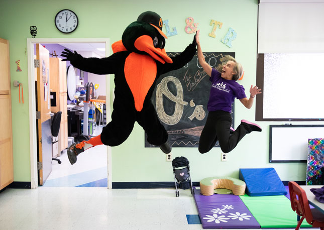 Jamie Kurman, director of Patient and Community Engagement, leaps and high fives the Oriole Bird.