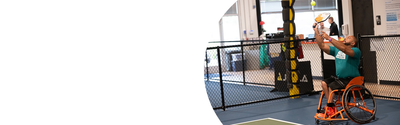 A male adaptive athlete makes a serve during a pickleball tournament.