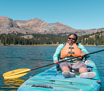 A child on a paddle board in a lake.