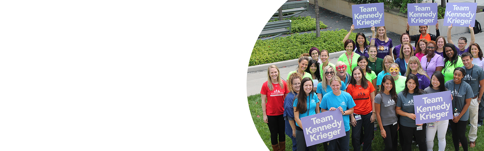 Smiling staff members holding Team Kennedy Krieger signs in Kennedy Krieger's Therapy Garden.