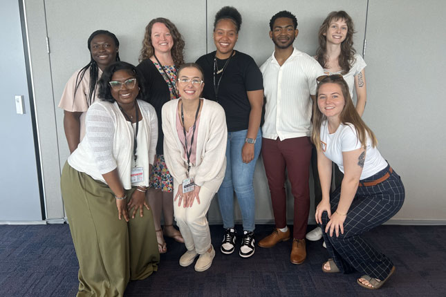Seven Neurodiversity at Work trainees and a staff member smile in a group photo.