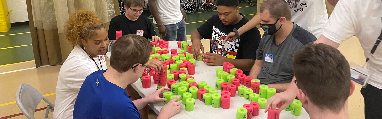 Neurodiversity at Work interns sit a table organizing green and read cylinders.