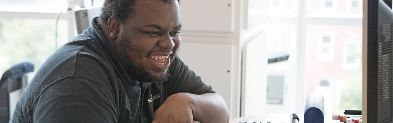 A Project SEARCH intern smiles while working at his computer.