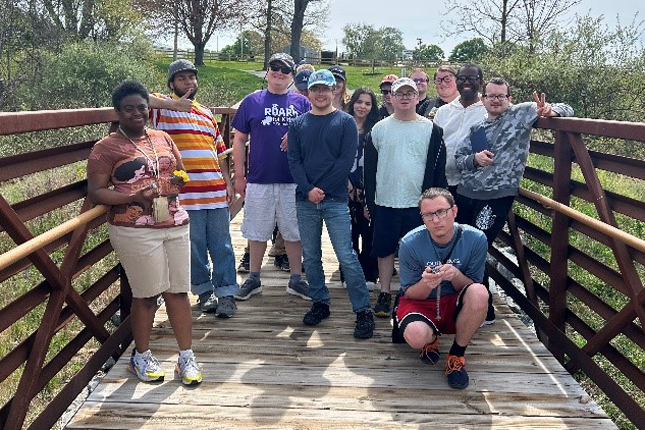 A group of CORE Foundations participants standing on a wooden pedestrian bridge at a park