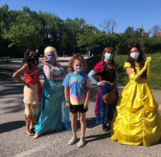 Disney Princess pose for a photo with a young girl at ROAR for kids.