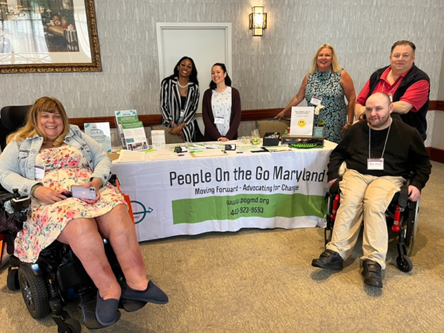 People on the Go Maryland team surrounds the POG exhibitor table at The Arc Maryland State Convention.