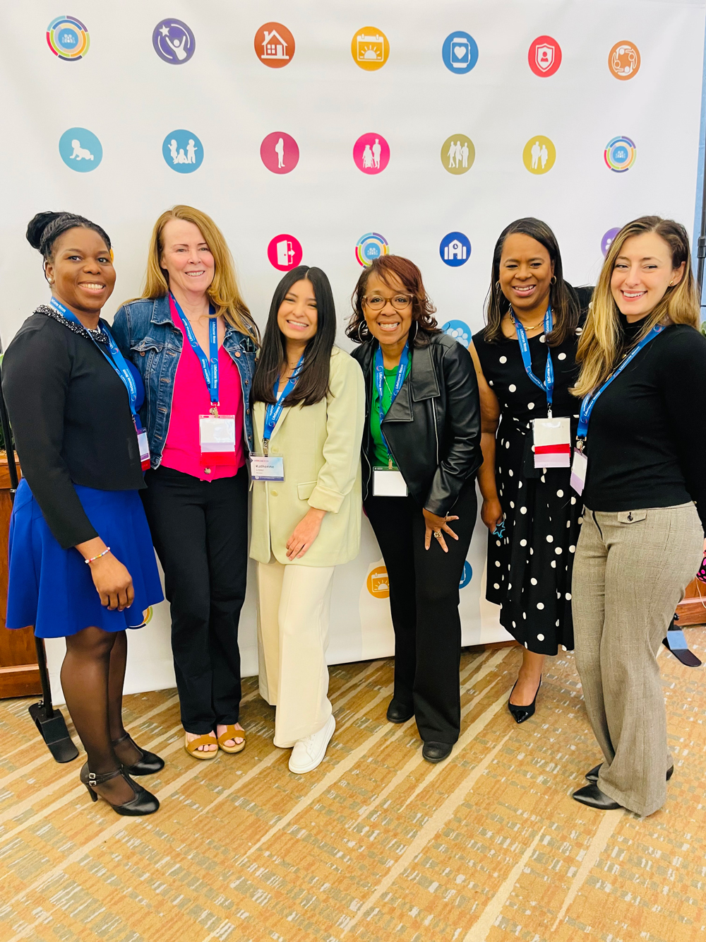Six women stand in front of a banner at the Charting the LifeCourse (CtrLC) Showcase .