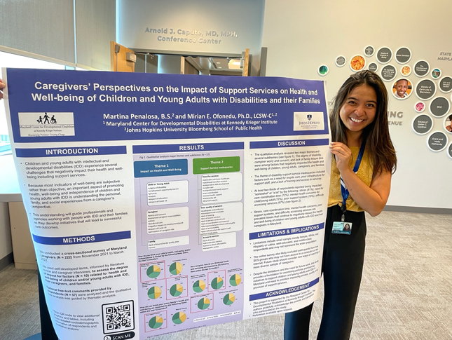 Martina Penalosa smiles as she stands next to her research poster, entitled "Caregivers’ Perspectives on the Impact of Support Services on Health and Well-being of Children and Young Adults with Disabilities and their Families